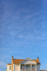 Upper storey of home againt sky with wispy clouds