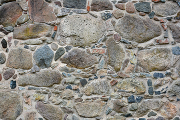 Stone wall of the old castle of granite rocks, old masonry. Texture, stonework.