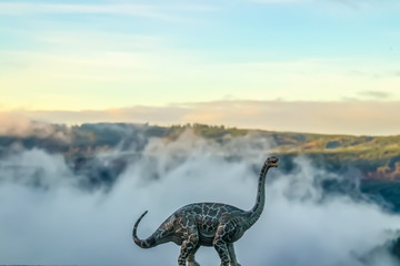 A brontosaurus or thunder lizard dinosaur roaring against a blurred misty mountain background -...