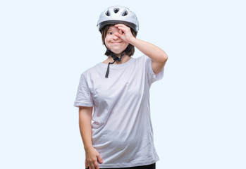 Young adult cyclist woman with down syndrome wearing safety helmet over isolated background doing ok gesture with hand smiling, eye looking through fingers with happy face.
