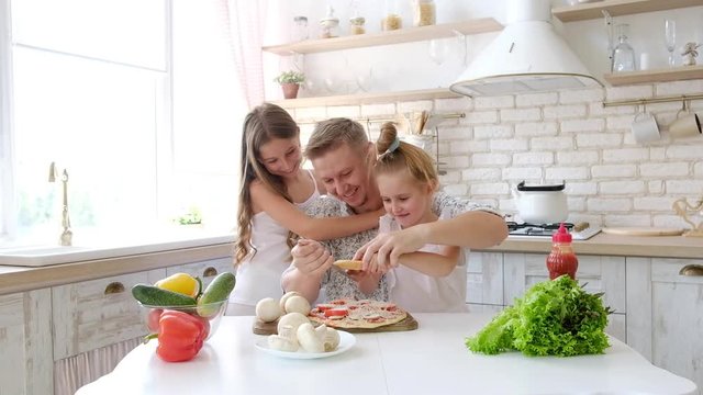 Father and daughters having a fun in the kitchen and making pizza