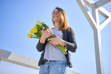 Girl with flowers standing outside in sunny weather