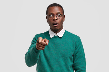 Omg look at this. Stupefied dark skinned man points with index finger at camera, dressed in casual...