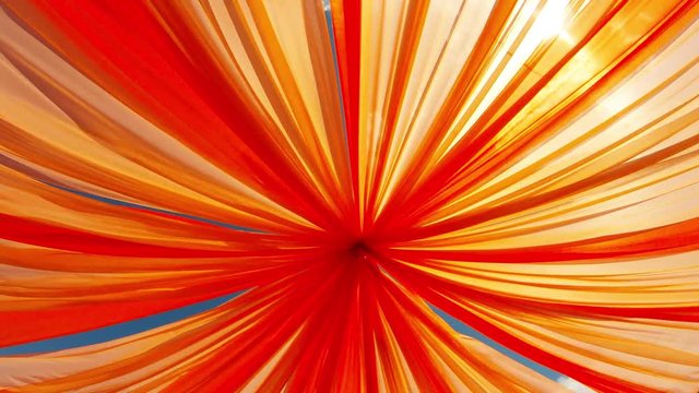 Throgh soft orange cloth swaying in wind sun and blue sky beautifully appear