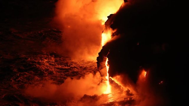 Lava flowing in the ocean and huge rock falls breaking off from volcanic lava eruption on Big Island Hawaii. Lava meets the Ocean in dramatic spectacle. Kilauea volcano. Night shot slow motion.