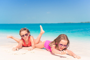 Fototapeta na wymiar Two little happy girls have a lot of fun at tropical beach playing together