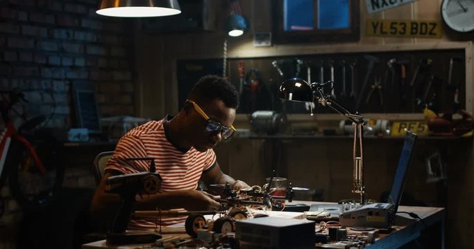 Slow motion shot of a man repairing a drone in a garage