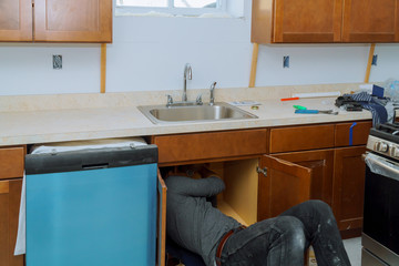 Man repairing sink pipe in the kitchen plumber fitting pipes