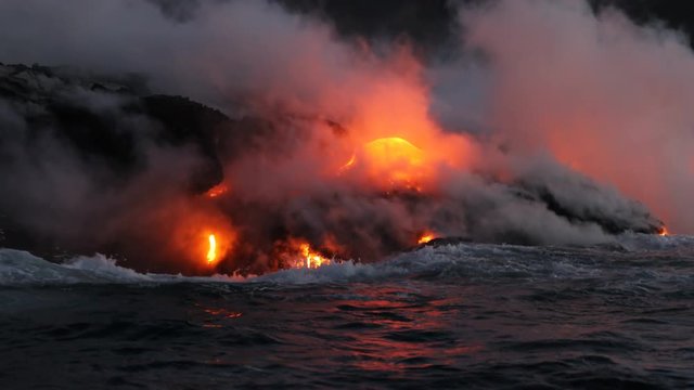 Hawaii Lava ocean close up - Lava running in the ocean from Kilauea volcano, Hawaii. Lava stream seem from lava boat tour flowing from volcanic eruption on Big Island, USA. Dawn Slow motion.