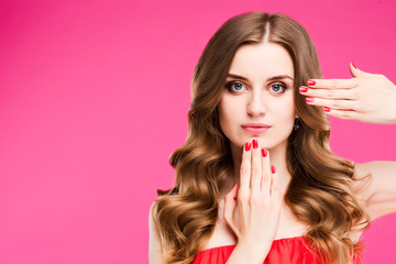 Portrait of beautiful red haired woman posing at camera and touching by arms with red manicure her face. Concept of Beauty shooting, skin care, hair, manicure. Studio shot on pink background