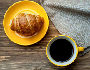 mug of coffee, croissant on wooden background