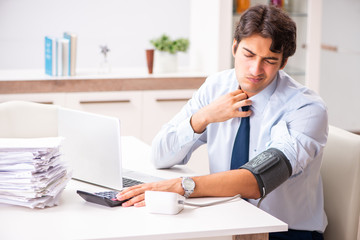 Man under stress measuring his blood pressure