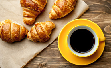 mug of coffee, croissants on wooden background