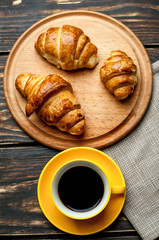 mug of coffee, croissants on wooden background