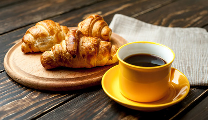 mug of coffee, croissants on wooden background