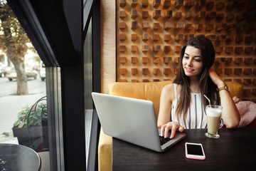 Young pretty caucasian woman in cafe in city centre with tablet laptop