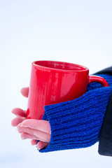 The red mug in hands on a winter background