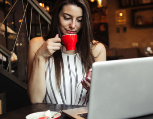 Young pretty caucasian woman in cafe in city centre with tablet laptop
