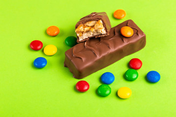 Tasty chocolate bars with toffee and nuts and colorful glazed round candies