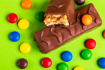 Tasty chocolate bars with toffee and nuts and colorful glazed round candies
