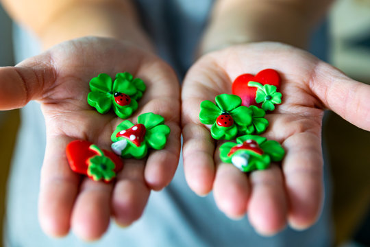 Frau h&auml;lt verschiedene Gl&uuml;cksbringer in den H&auml;nden, es sind Kleebl&auml;tter, Herzen und Pilze