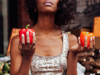 woman holding red and orange pepper in her hands 
