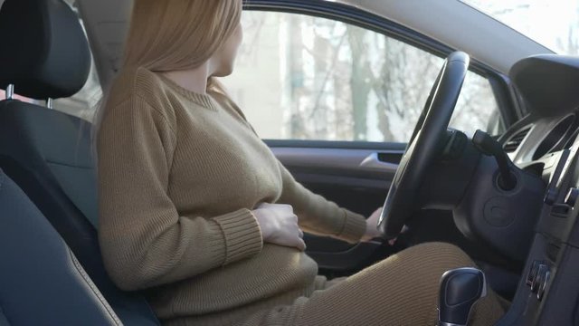 young pregnancy girl with big stomach gets in salon car close-up and getting ready for driving