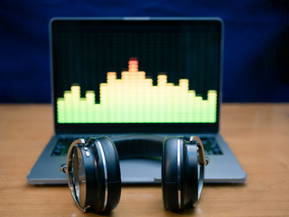 professional headphones lays on laptop with equalizer