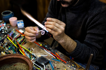Fototapeta premium a glassblower man made Handicraft from melted glass in glassblowing workshop. Glass art is shaping at the end of glassblowing pipe. 