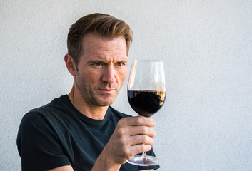 handsome Caucasian man holding a glass of red wine