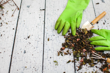 Rubber green safety gloves hand shovel and gardening rake on wooden board agriculture concept.