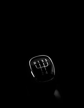 Manual gearbox in the car on black background, space for text