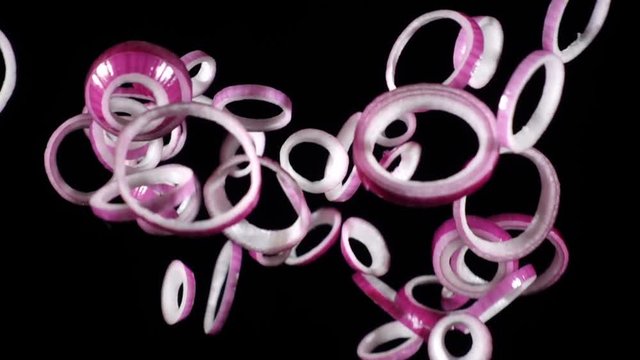 Falling rings of red onion slices, slow motion