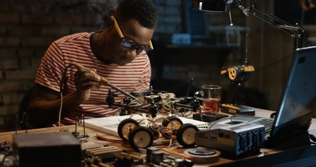 Slow motion shot of a black man repairing a drone in a garage