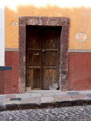 Rustic old wooden doorway set against a colorful painted wall in San Miguel de Allende, Mexico