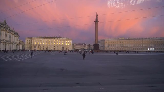 Palace Square The best shots in St. Petersburg. Winter Palace Hermitage Museum facade. Alexander column with an angel and a cross. People walking, evening twilight.