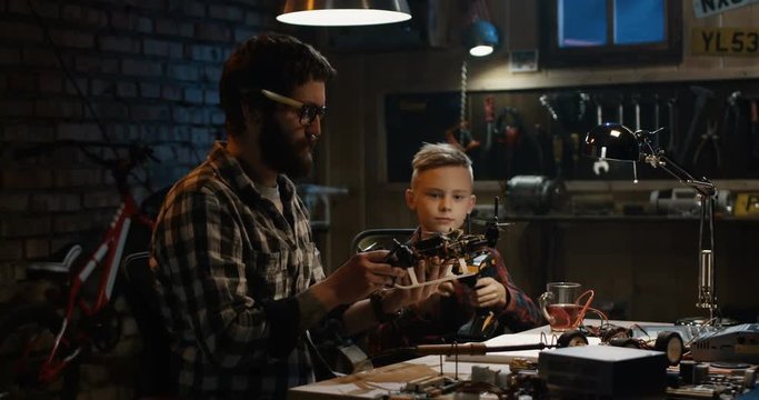 Medium shot of a father and son repairing a drone in a garage