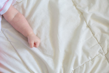 Hand baby clenched into a fist on the bed. The child is sleeping. Hands of a child in a tone.
