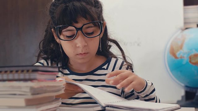 Close up of cute caucasian girl with glasses writing homework at home, 4k