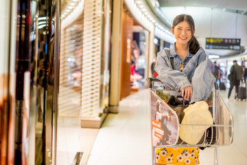 Woman with Happy smile of shopping day at airport terminal with bags and shopping cart on hand