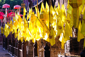 Yellow flags and lanternes decorating Buddhist temple courtyard, Thailand