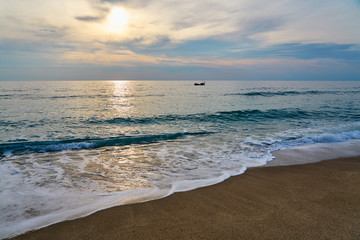 Fototapeta na wymiar Silhouette of a ship on the sea on a sunset with waves on the beach.