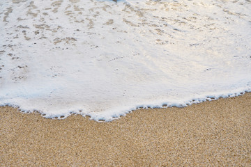 White foam on a sandy beach. Copy space.