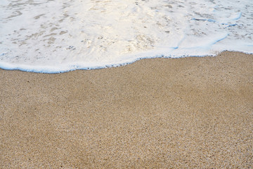 White foam on a sandy beach. Copy space.
