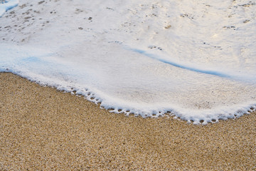 White foam on a sandy beach. Copy space.