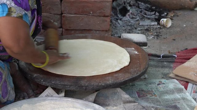  Indian woman cooking traditional indian bread, big chapati cooking on open fire in Udaipur, Rajasthan, India. Close up