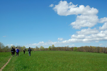 People hiking in a wide meadow under a beautiful big blue sky 