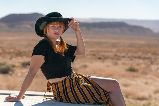 Ginger cowgirl with skirt and black top in the desert