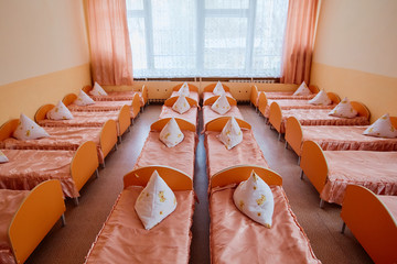 Beds and cots in brightly colored dormitory of a nursery.A lot of children's cots