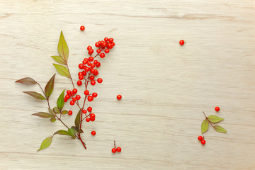 Christmas Red berries of sacred bamboo (Nandina Domestica) flowers on wooden background.